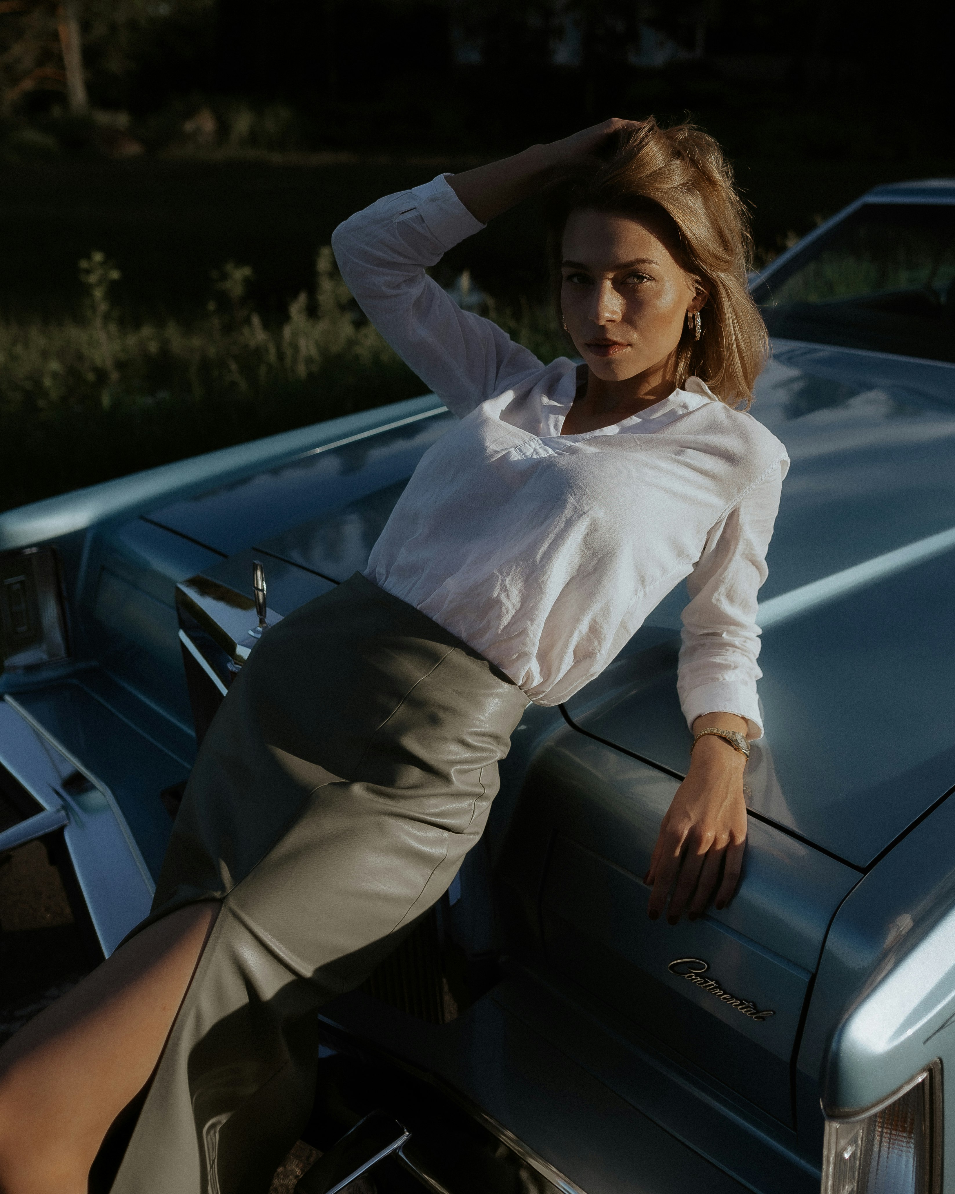 woman in white dress shirt and black skirt sitting on black car